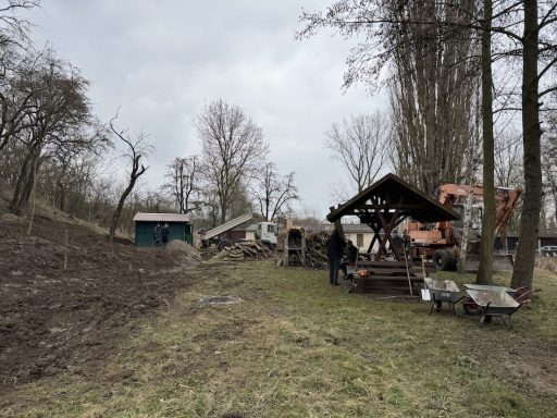 Landschaft mit Werkzeugen, Holzständen und Bäumen in bewölkter Umgebung.
