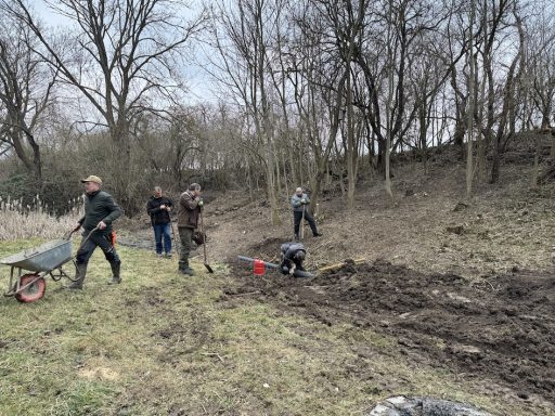 Menschen arbeiten im Freien, einige graben, andere nutzen eine Schubkarre.