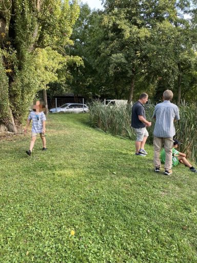 Familie im Freien: Kinder und Erwachsene spielen und erkunden die grüne Umgebung.