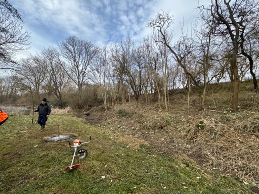 Person steht neben einem E-Scooter in einer bewaldeten, lichten Umgebung.